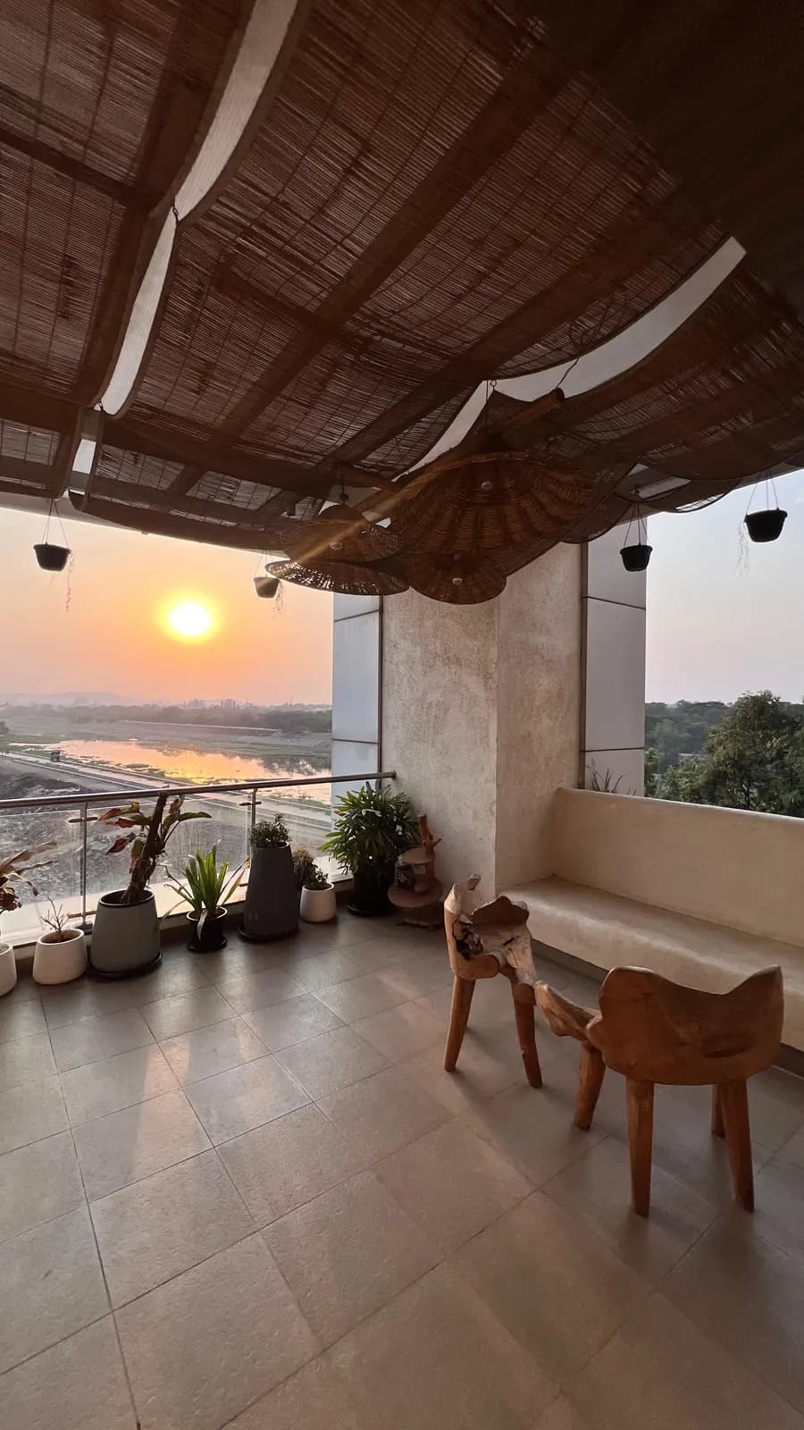 The balcony at Mindsight Clinic, Boat Club Road, Pune, with wooden chairs and plants, looking over the river at sunset