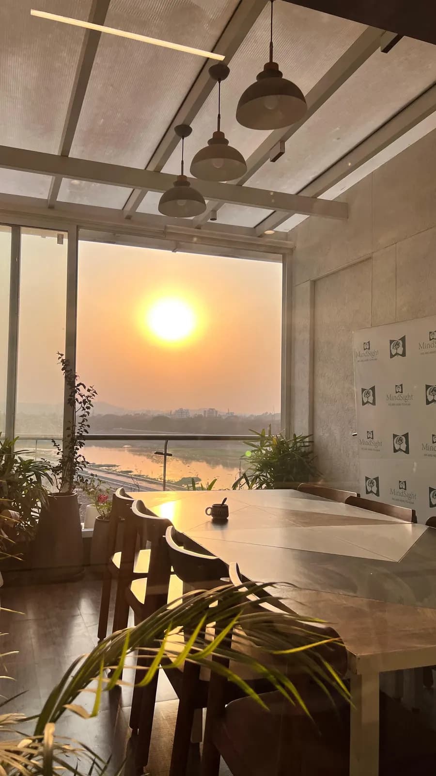 A long wooden table by the windows at Mindsight Clinic, Boat Club Road, Pune, with the sun setting over the river